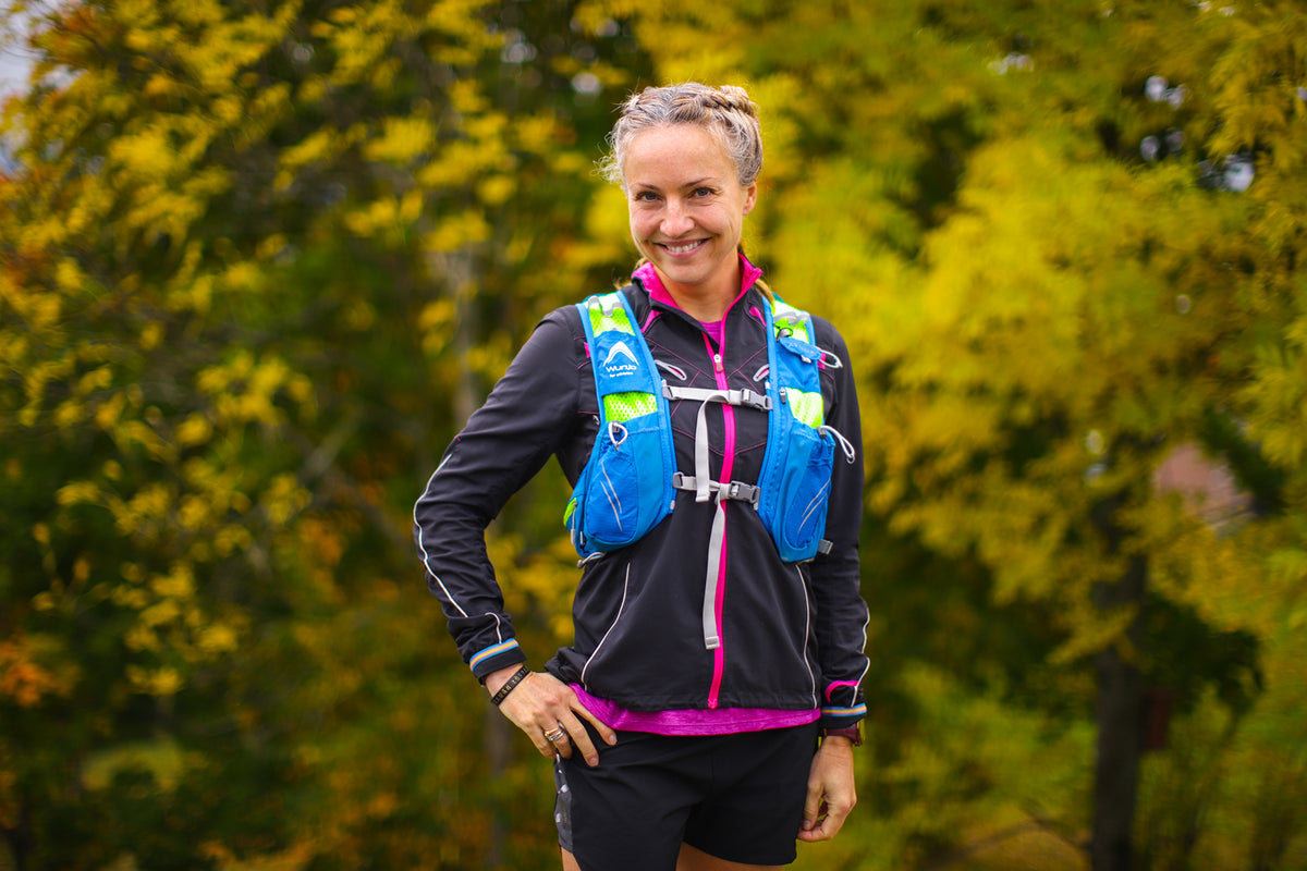 sporty kvinne står foran grønne trær